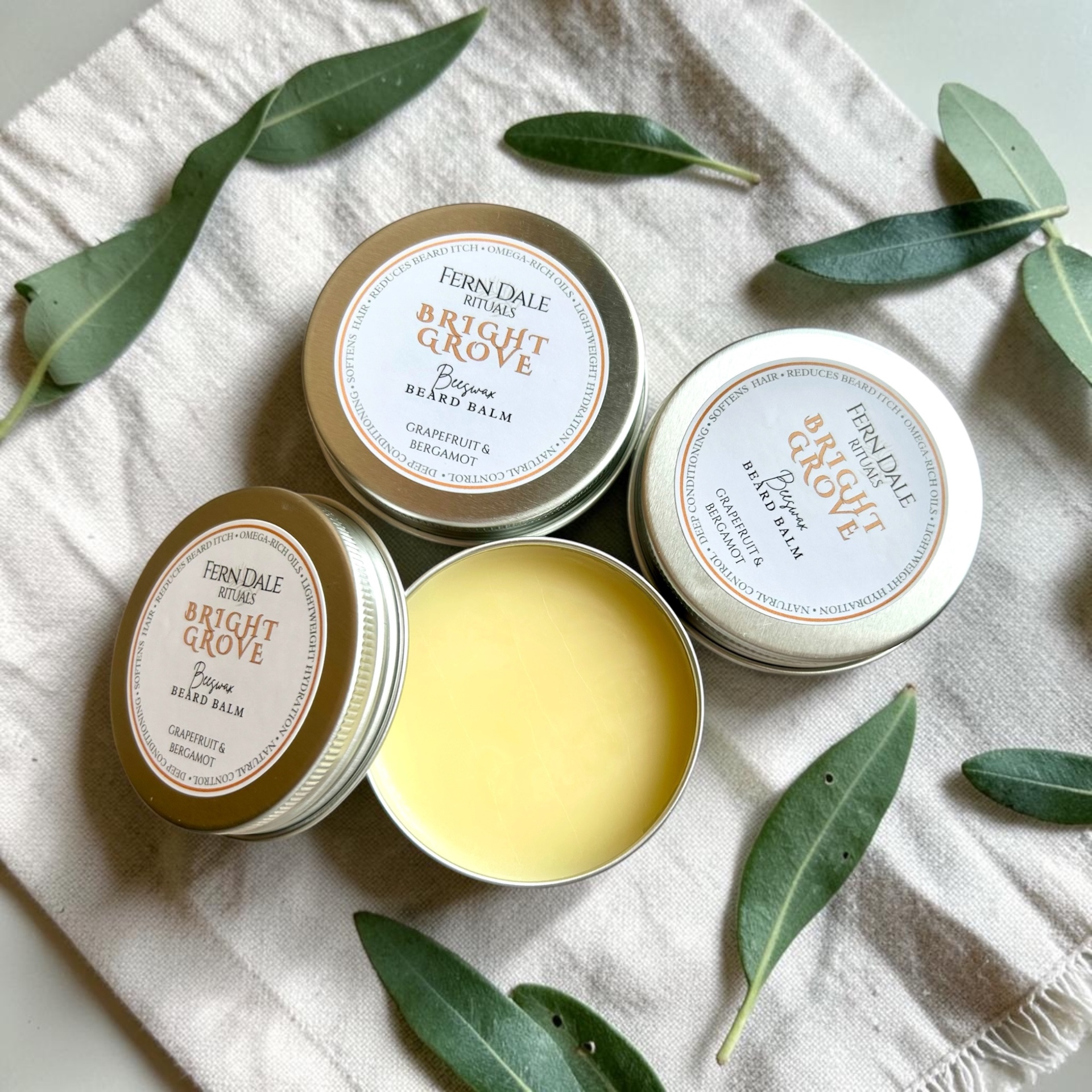 Fern Dale Rituals Bright Grove beeswax beard balm tins with eucalyptus leaves.