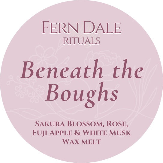 Beneath the Boughs round pink wax melt label with burgundy lettering and pale floral outlines.