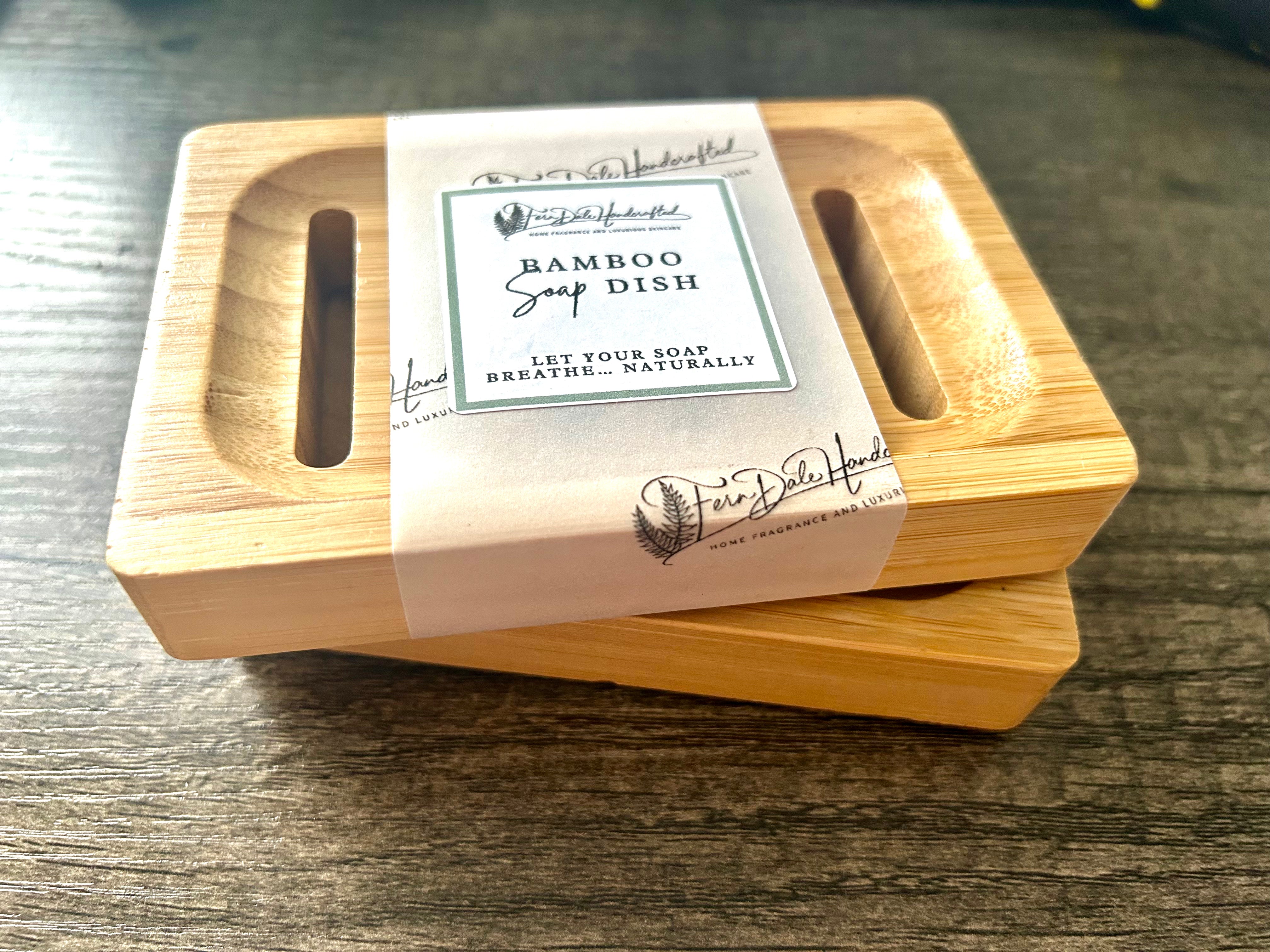 Bamboo Soap Dish with rounded corners, long slots and a printed paper band, stacked on another dish on a wooden surface.