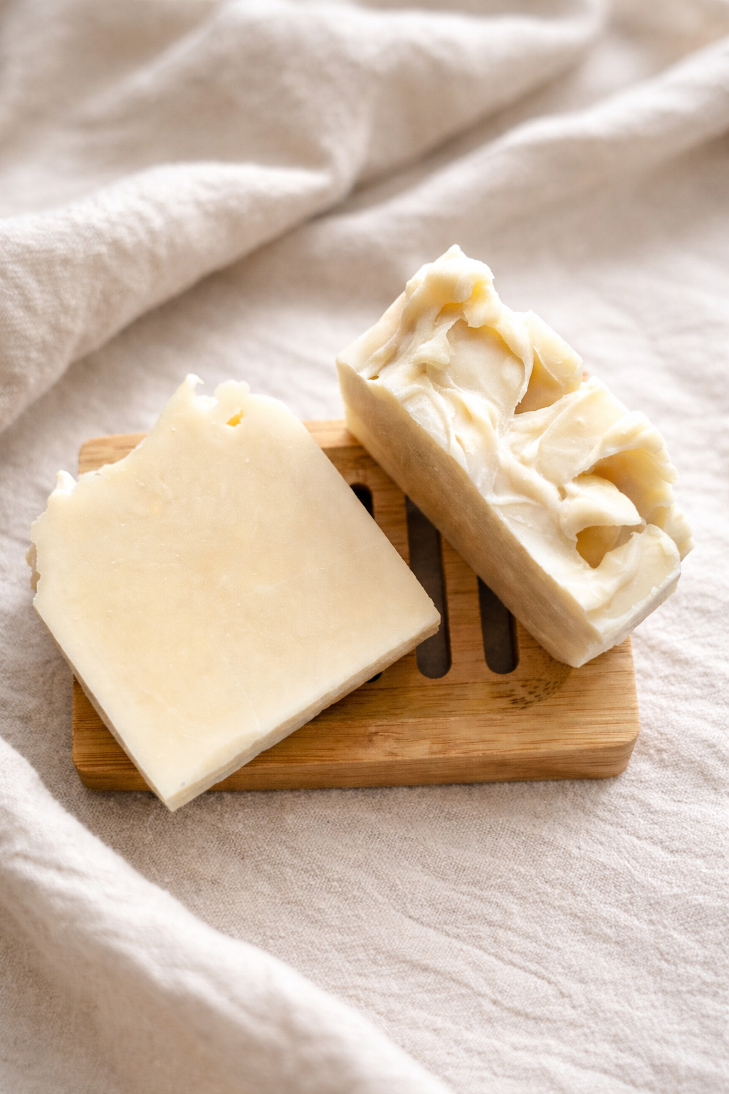 Moo Point Tallow Soap Bar shown as two cream-coloured bars with textured tops on a wooden soap dish.