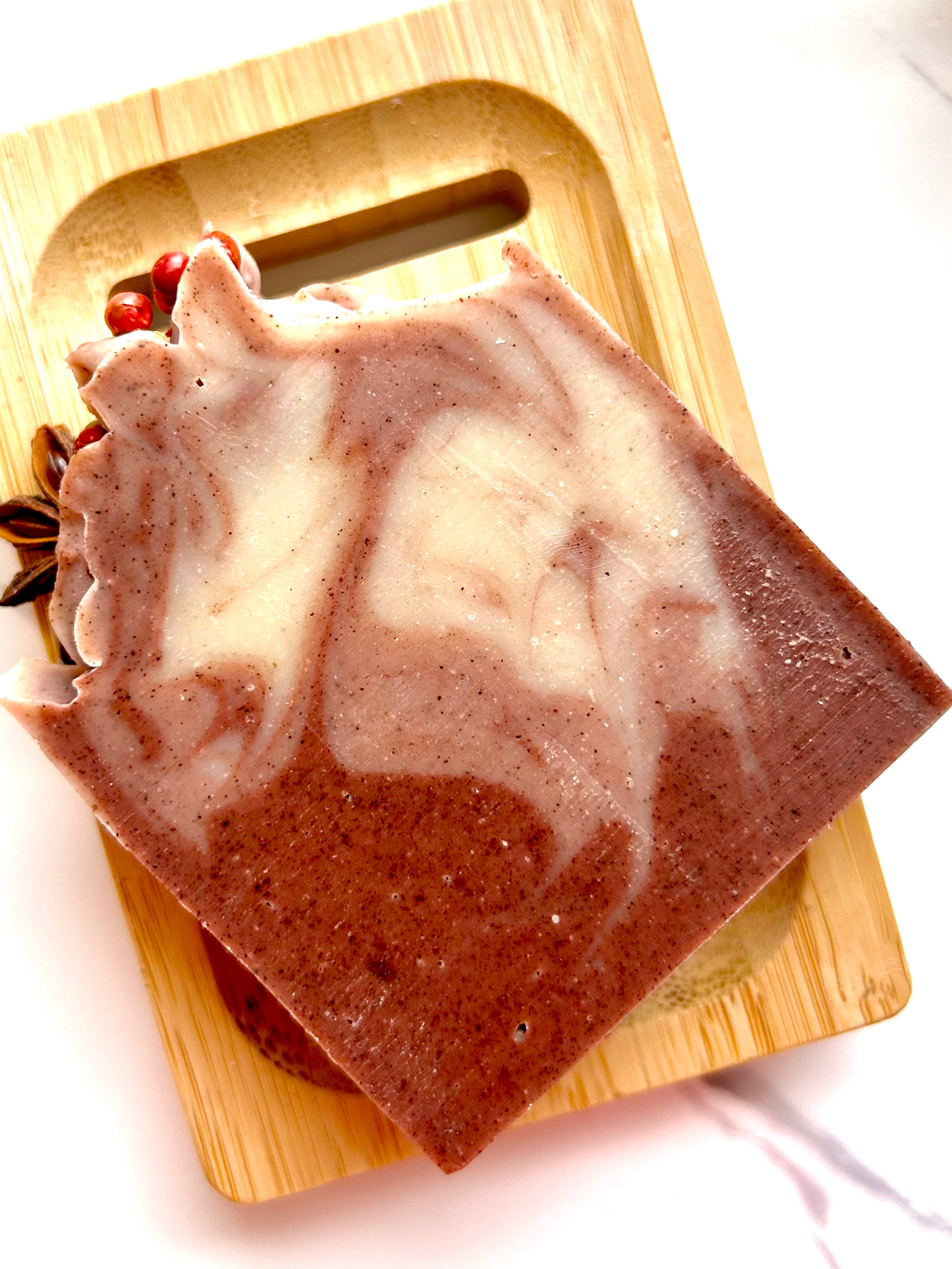 Hearth Light - Clove, Cinnamon & Sweet Orange (Fire) Tallow Soap with pink and cream swirls on a wooden dish.